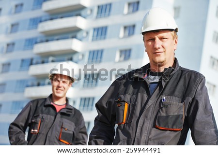Team of smiling foreman builders workers in protective uniform at construction building site