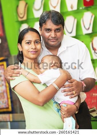 Happy smiling Indian family portrait with little child in a shop
