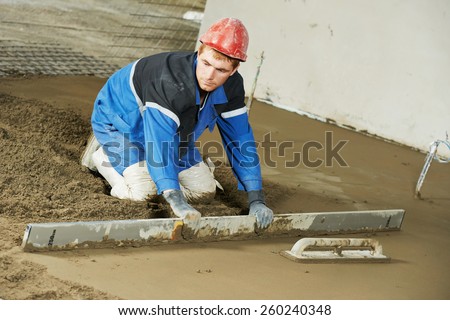 Plasterer at indoor concrete cement floor topping with float