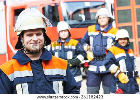firefighter in uniform in front of fire engine machine and fireman team
