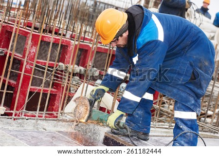 Construction builder worker with grinder machine cutting metal reinforcement rebar rods at building site