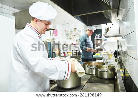 male cooks chef in uniform cooking at restaurant kitchen