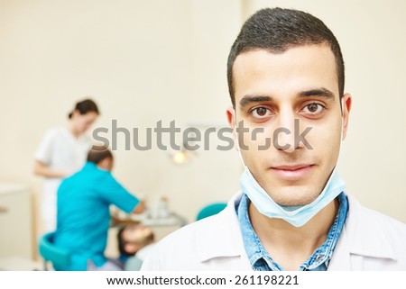 Portrait of male asian dentist wearing lab coat while sitting in clinic