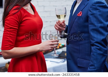 Party. Two guests of formal evening party celebration holding glasses of wine in their hands