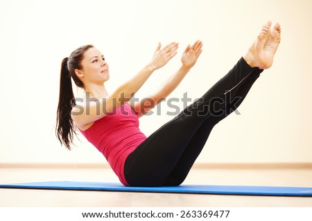 young female instructor doing stretching pilates exercises in sport club