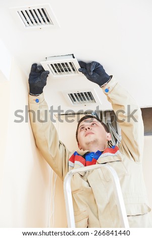 industrial worker installing ventilation or air conditioning filter holder in ceiling