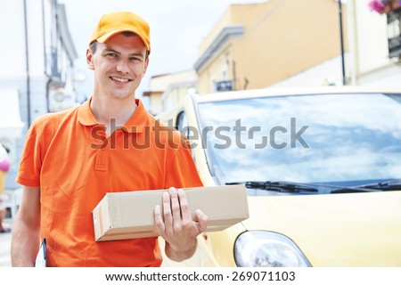 Smiling postal delivery courier man outdoors  in front of cargo van delivering package