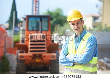construction worker in safety protective work wear at construction site in front of loader machinery