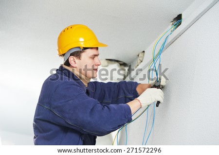 Male electrician at work laying wiring cable