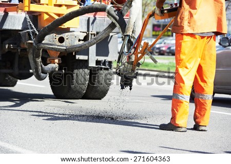 Road worker at asphalt roadway street patching reaparing work