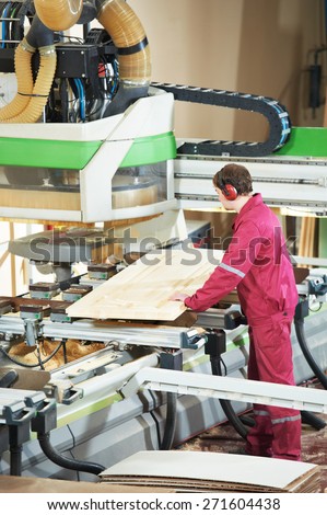 industrial carpenter worker operating wood cutting machine during wooden door furniture manufacturing