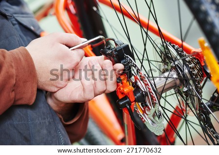 Mechanic serviceman repairman installing assembling or adjusting bicycle gear on wheel in workshop