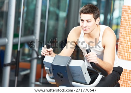 young man at cardio training on bicycle machine station in fitness gym