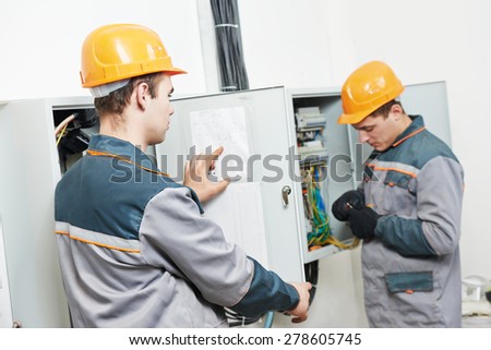electrician builder engineer workers with electric cable wiring of fuse switch box