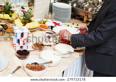 Hotel restaurant catering service. Man with food at morning buffet style smorgasbord breakfast
