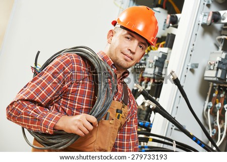electrician engineer worker with cable in front of fuseboard equipment