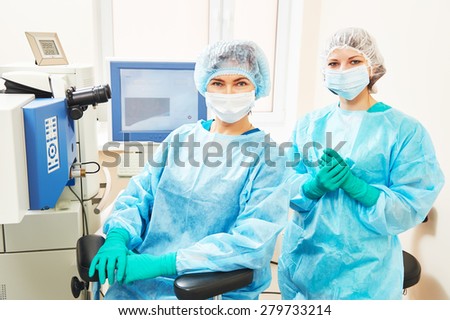 Female surgeon and assistant nurse portraits in uniform in eye vision surgery operation room at medical clinic