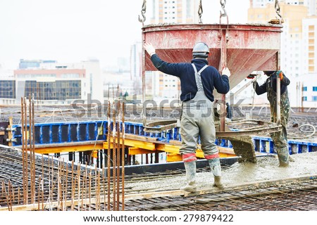 concreting work: construction site worker during concrete pouring into formwork at building area with skip