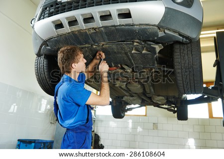 garage auto mechanic repairman assembling bottom car protection during car suspension repair of automobile maintenance at repair service station