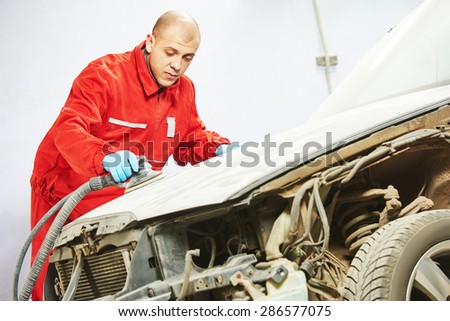 auto mechanic worker sanding polishing car at automobile repair and renew service station shop by sandpaper