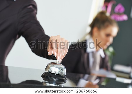 female receptionist worker ringing at hotel counter bell