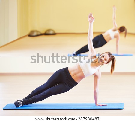 Plank. young female instructor doing stretching pilates exercises in sport club
