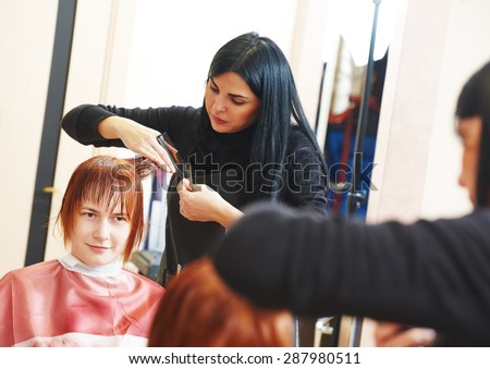 Stylist cutting hair of a female client at the beauty salon