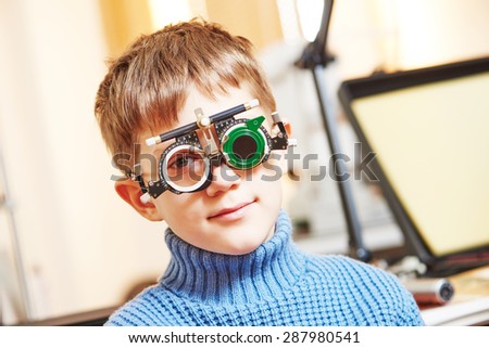 ophthalmology concept. young boy with phoropter during sight testing or eye examinations in clinic