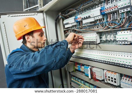 electrician with screwdriver tighten up switching electric actuator equipment in fuse box