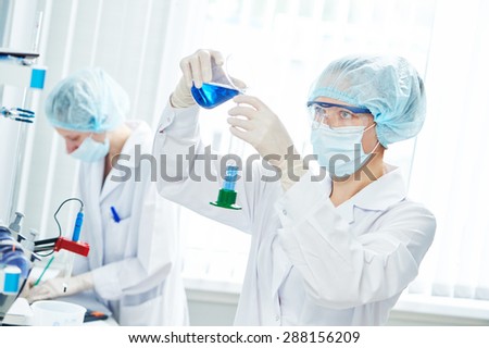 science laboratory work. female scientific researcher or doctor working with flask and blue liquid solution