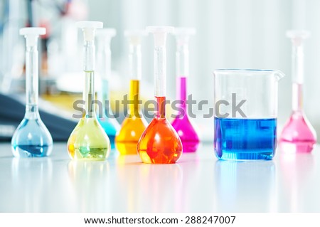 Pharmacy and chemistry theme. Test glass flask with solution in research laboratory. Shallow DOF. Focus on red bottle.