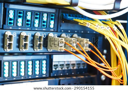 technology equipment with optical fibre cables connected to rack servers in room. Shallow DOF