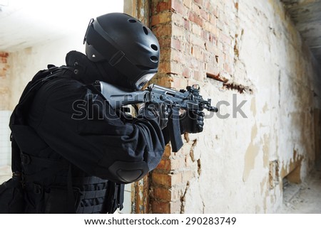 Military industry. Special forces or anti-terrorist police soldier,  private military contractor armed with assault rifle ready to attack during clean-up operation, mission