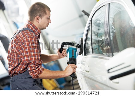 auto mechanic worker polishing car body at automobile repair and renew service station shop by power buffer machine