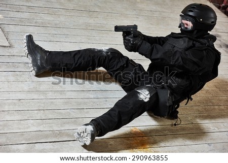Military industry. Special forces or anti-terrorist police soldier,  private military contractor armed with pistol ready to attack lying on ground during clean-up operation, mission