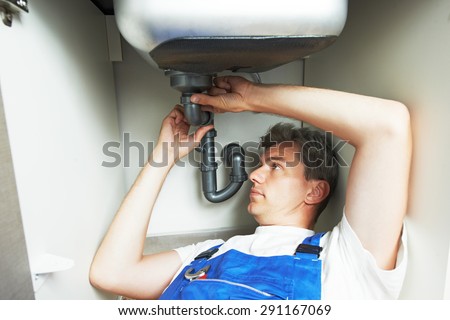 Young plumber worker repair or installing kitchen sink with spanner