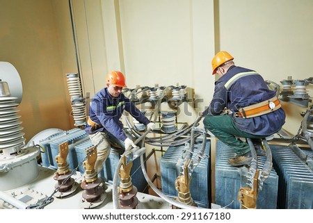Electricians lineman repairman worker at huge power industrial transformer installation work