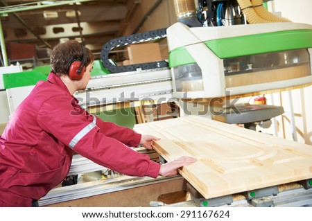 industrial carpenter worker operating wood cutting machine during wooden door furniture manufacturing