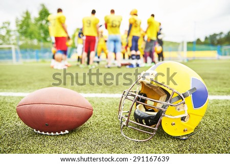 American football helmet and ball lying on field