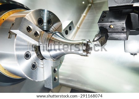 metalworking  industry: cutting steel metal shaft processing on lathe machine in workshop. Selective focus on tool