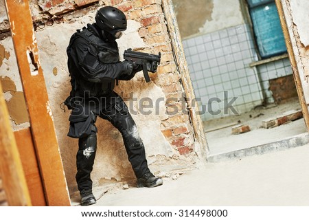 Military industry. Special forces or anti-terrorist police soldier,  private military contractor armed with assault rifle ready to attack during clean-up operation, mission
