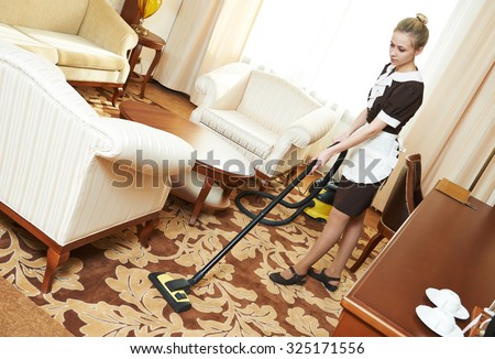 Hotel cleaning service. female housekeeping worker with vacuum cleaner in room apartment