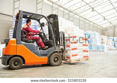 warehousing. Forklift driver stacking pallets with cement packs by stacker loader