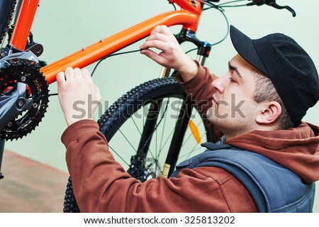 Bike maintenance: mechanic serviceman repairman installing assembling or adjusting bicycle gear on wheel in workshop