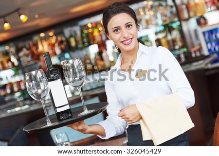 waiter restaurant catering service. Female cheerful worker with tray, glasses and bottle of wine