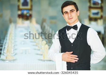 Male cheerful waiter in restaurant readu to service