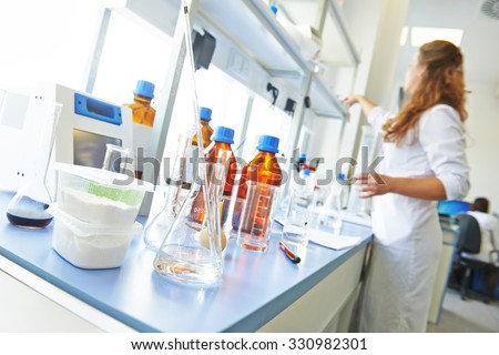 Pharmacy and chemistry theme. Container of powder and test glass flask with solution in research laboratory. Shallow DOF