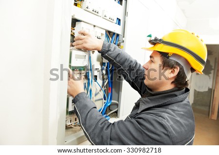 electrician builder at work installing energy saving meter into electric line distribution fuseboard