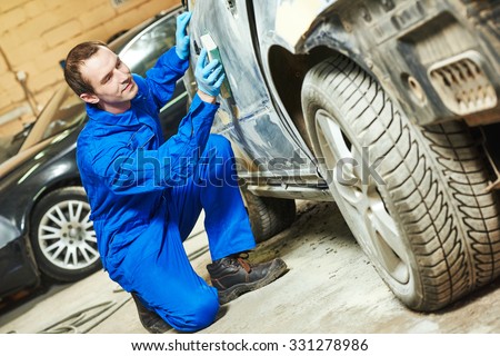 auto mechanic worker sanding car body at automobile repair and renew service station shop by sandpaper