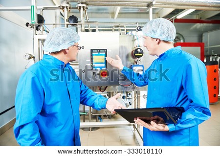 Two pharmaceutical male workers operating air conditioning equipment at pharmacy industry manufacture factory using notebook computer